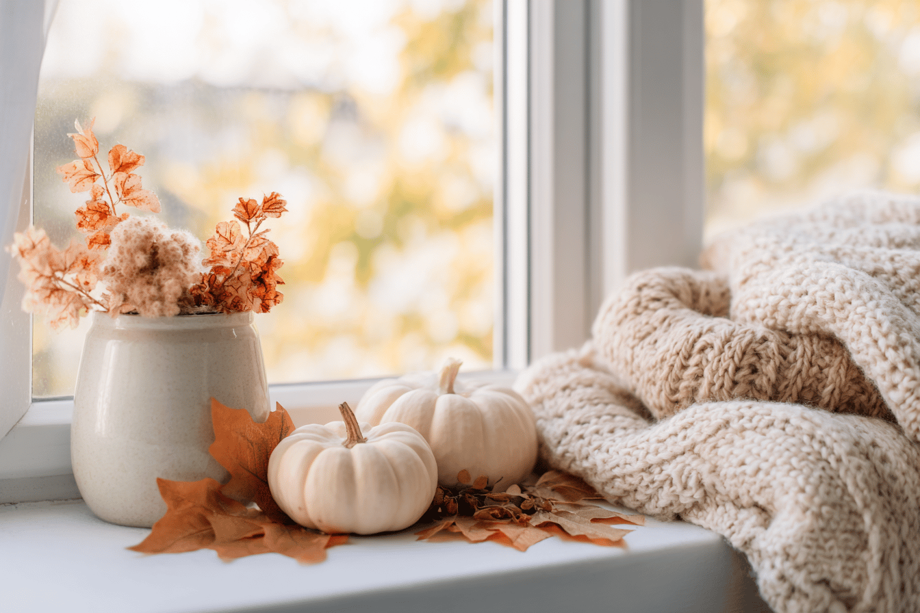 Herbstdeko mit Kürbissen und Strickdecke am Fenster