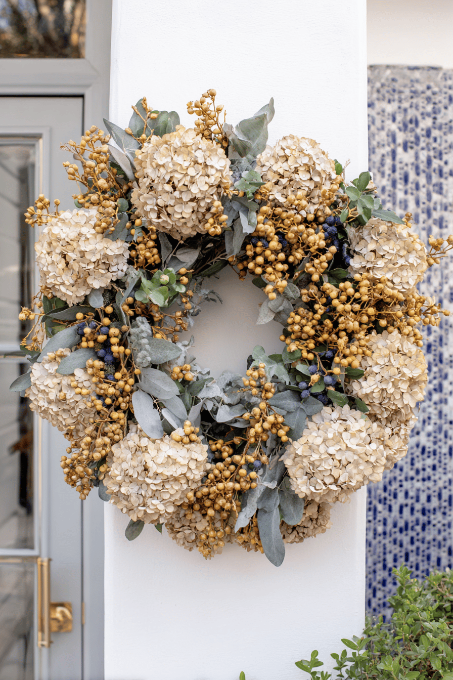 Herbstkranz mit getrockneten Hortensien, goldenen Beeren und grünen Blättern.