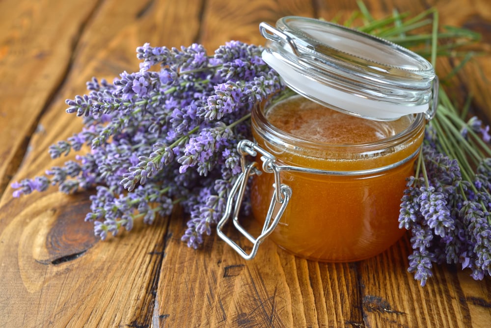 Glas mit goldenem Lavendel-Honig und frischen Blüten