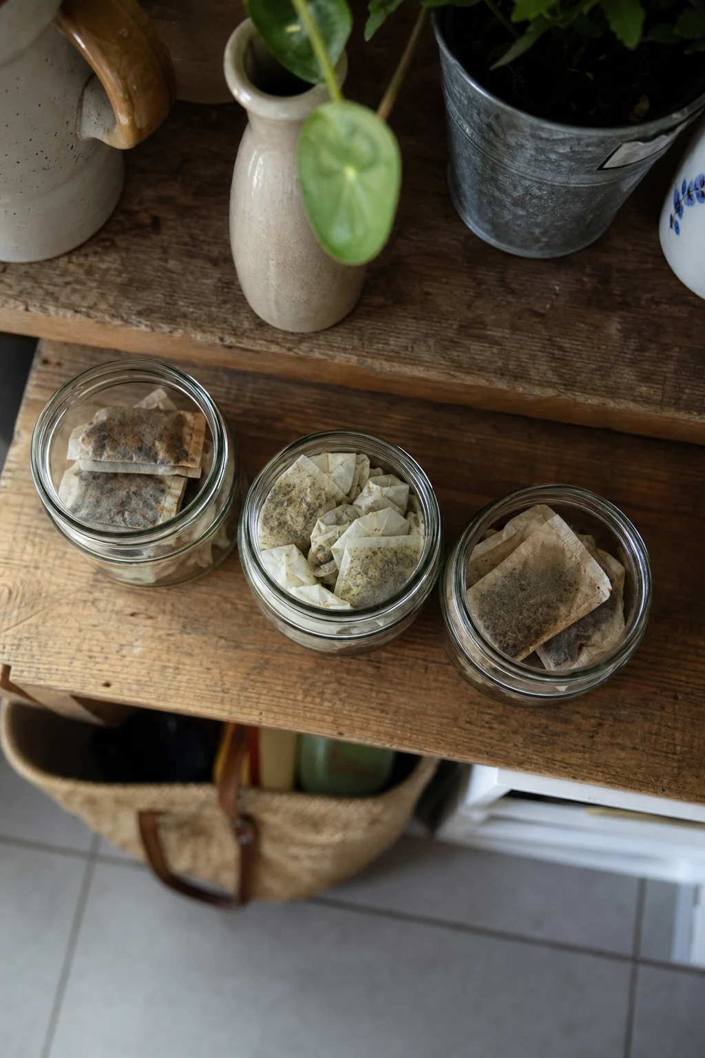 Drei Einmachgläser mit getrockneten Teebeuteln auf einem Küchenregal, beschriftet als Kühlschrank-, Vorrats- und Schuh-Deodorierer.